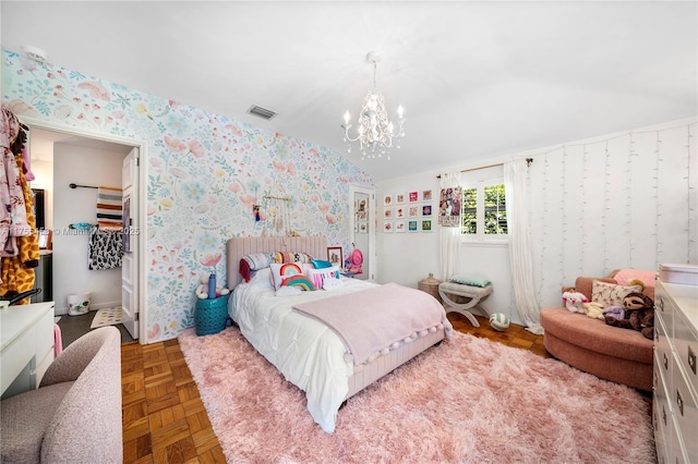 bedroom featuring a notable chandelier, visible vents, vaulted ceiling, a walk in closet, and wallpapered walls