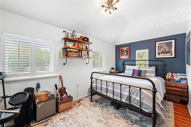 bedroom featuring a notable chandelier, vaulted ceiling, and wood finished floors