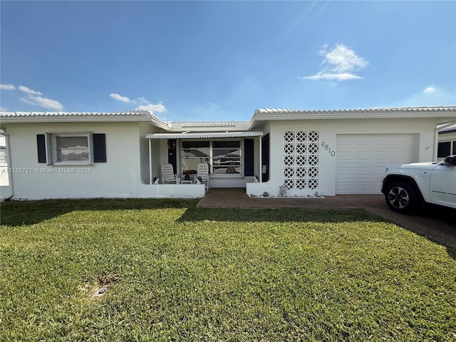 view of front facade featuring a front lawn, an attached garage, a tile roof, and stucco siding