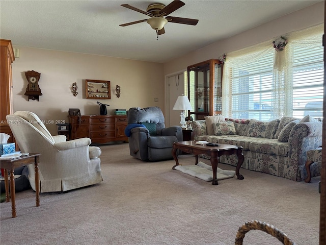 living area with light carpet, ceiling fan, and a textured ceiling