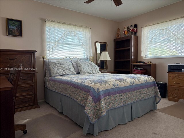 bedroom featuring ceiling fan, multiple windows, and light colored carpet