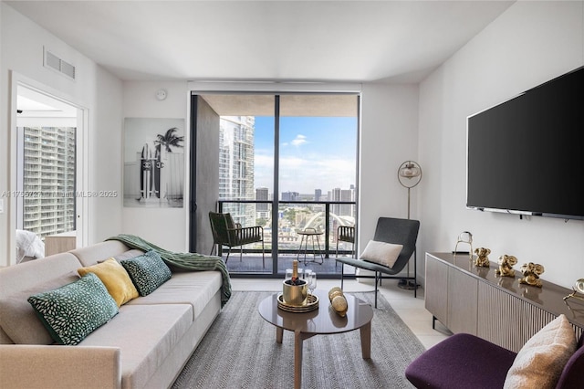 living room featuring light tile patterned floors, visible vents, and a wall of windows