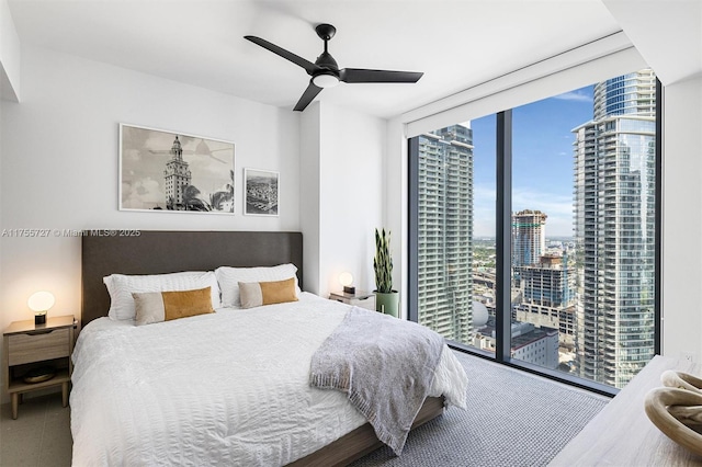 bedroom featuring expansive windows, access to outside, a view of city, and a ceiling fan