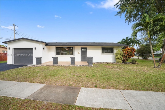 single story home featuring an attached garage, driveway, a front yard, and stucco siding