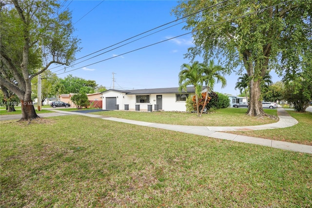 view of front of property with concrete driveway, an attached garage, a front lawn, and stucco siding