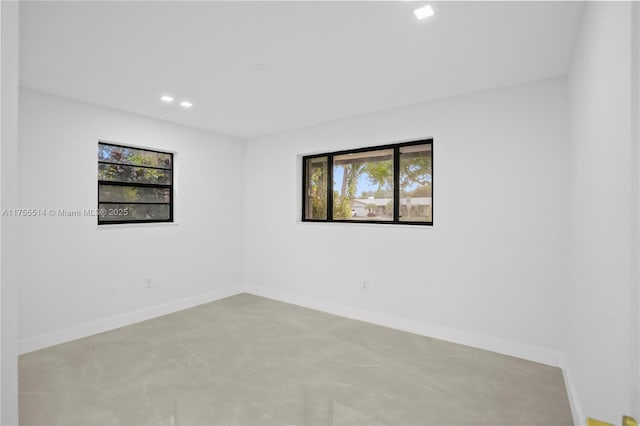 unfurnished room with a healthy amount of sunlight, concrete floors, recessed lighting, and baseboards