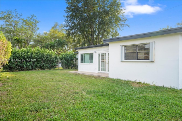 rear view of house with a yard and stucco siding