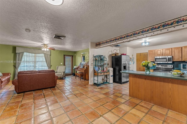 kitchen with stainless steel appliances, dark countertops, visible vents, open floor plan, and ceiling fan