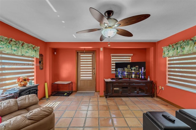 living area featuring ceiling fan, baseboards, and light tile patterned flooring