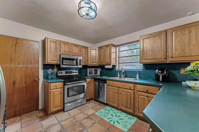 kitchen featuring stainless steel appliances, brown cabinetry, and a sink