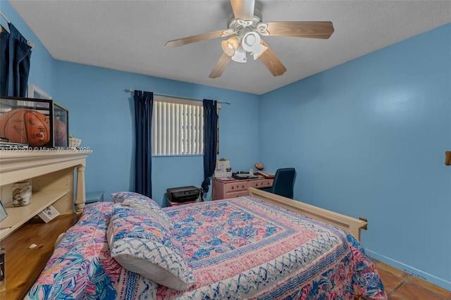 tiled bedroom featuring ceiling fan, a textured ceiling, and baseboards