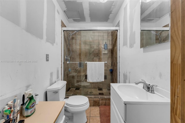 bathroom featuring toilet, a shower stall, vanity, and tile patterned floors