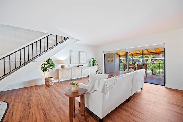 living area featuring baseboards, stairway, and wood finished floors