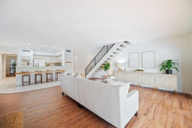 living room featuring stairway, recessed lighting, visible vents, and light wood-style flooring