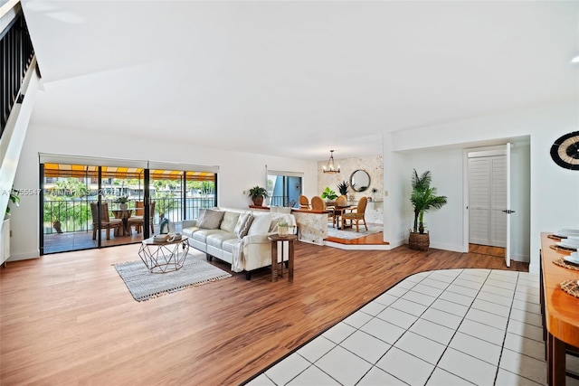 living room featuring light wood-type flooring, a notable chandelier, and baseboards