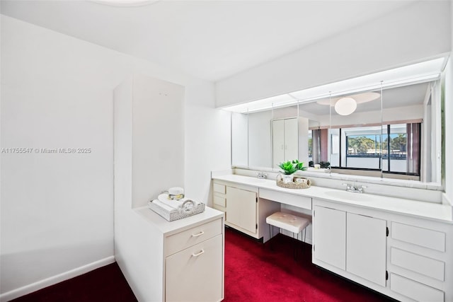 full bath featuring a sink, baseboards, and double vanity