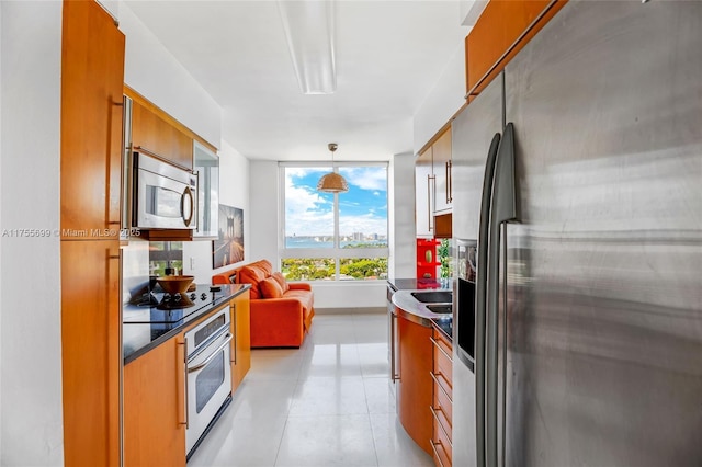 kitchen with brown cabinets, stainless steel appliances, dark countertops, hanging light fixtures, and modern cabinets