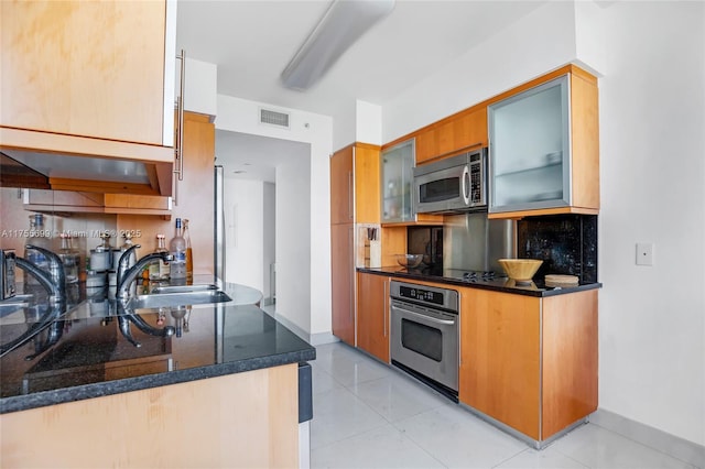 kitchen with visible vents, a sink, stainless steel appliances, backsplash, and light tile patterned flooring