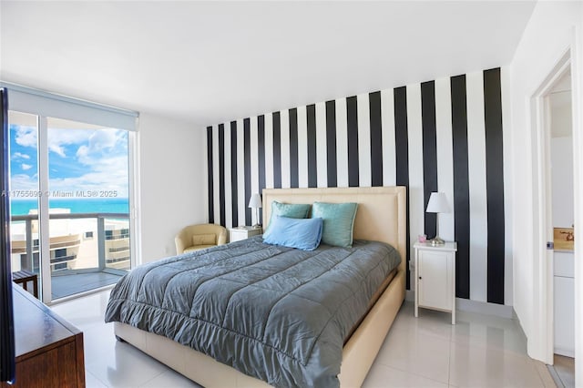 bedroom with light tile patterned floors, an accent wall, access to outside, floor to ceiling windows, and wallpapered walls