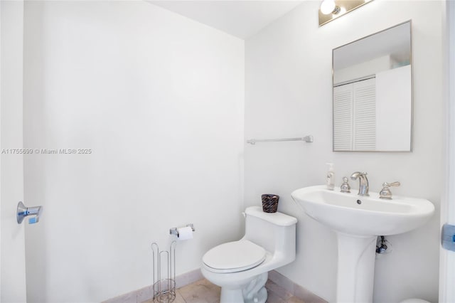 half bathroom featuring baseboards, toilet, and tile patterned floors