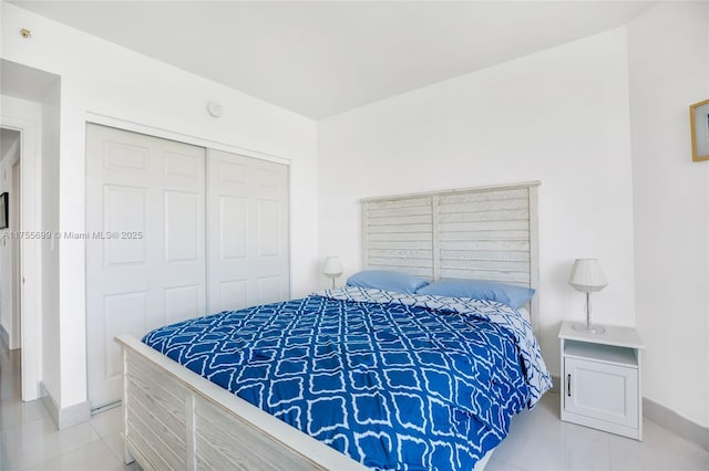 bedroom with light tile patterned floors, a closet, and baseboards