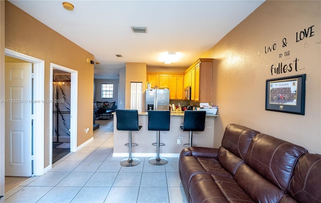 living area featuring light tile patterned floors, visible vents, and baseboards