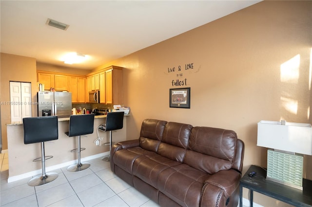 living room featuring light tile patterned flooring, visible vents, and baseboards