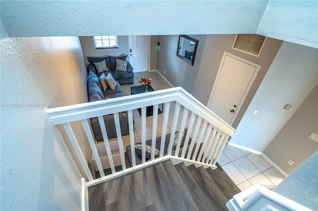 staircase with a textured ceiling, tile patterned flooring, visible vents, and baseboards