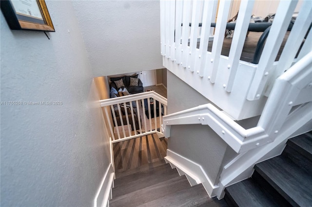 stairs with a textured wall and wood finished floors