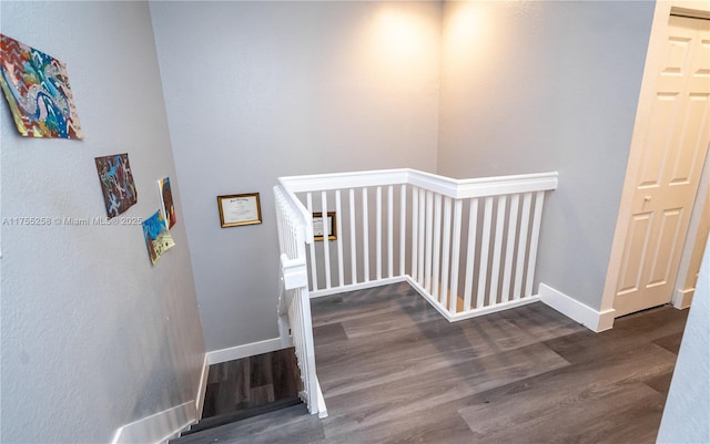 staircase featuring baseboards and wood finished floors