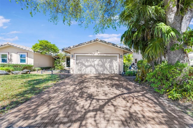 view of front of property with an attached garage, a front lawn, decorative driveway, and stucco siding