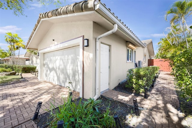 view of home's exterior with a garage, fence, and stucco siding