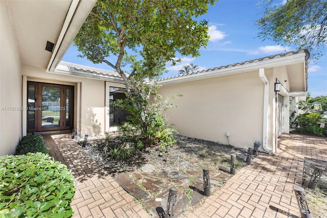 view of exterior entry with a tile roof and stucco siding