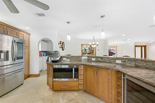 kitchen featuring beverage cooler, visible vents, appliances with stainless steel finishes, brown cabinetry, and decorative light fixtures