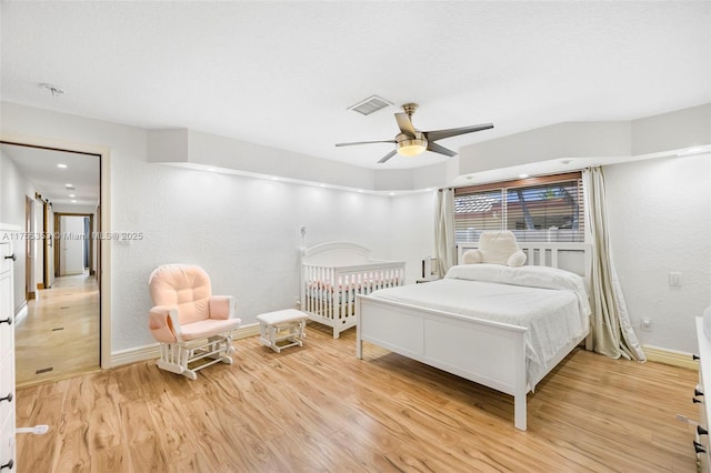 bedroom with light wood-style floors, visible vents, baseboards, and a ceiling fan