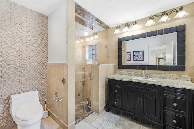 bathroom featuring toilet, a stall shower, vanity, and tile walls
