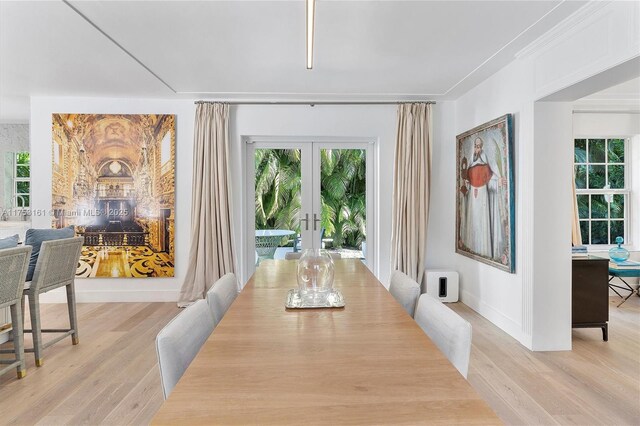 dining area with french doors, baseboards, and light wood-style floors