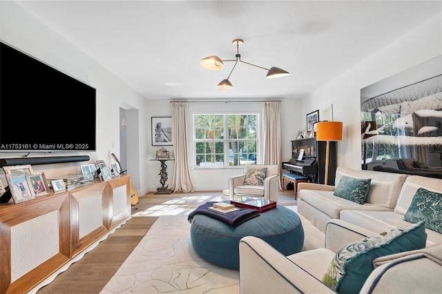 living area featuring a notable chandelier, baseboards, and wood finished floors