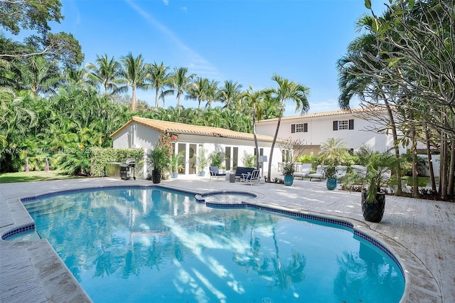 outdoor pool featuring an in ground hot tub and a patio area