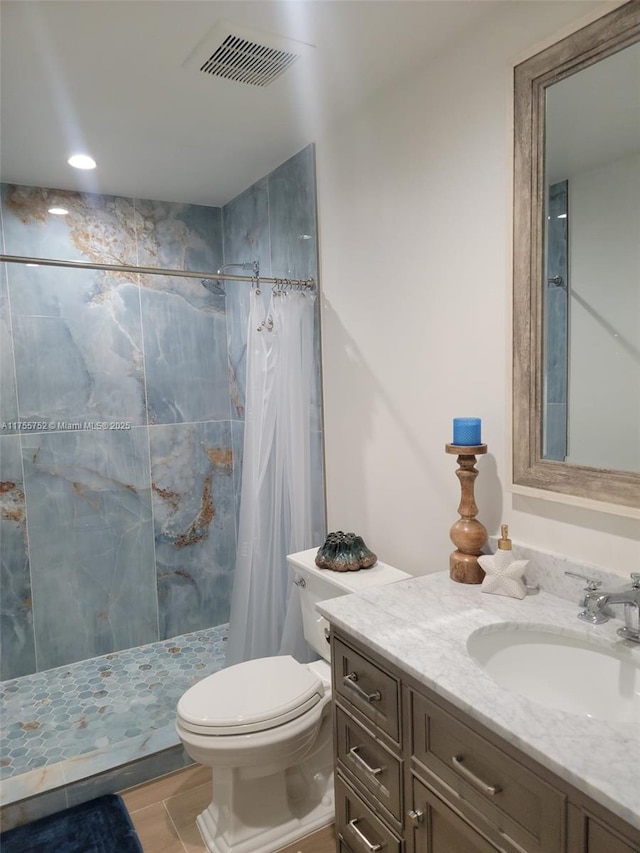 bathroom featuring toilet, a stall shower, visible vents, and vanity