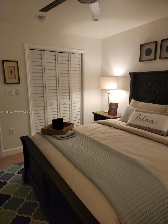 bedroom featuring a ceiling fan, a closet, baseboards, and dark wood-style flooring