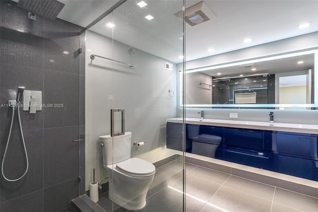 bathroom with tiled shower, double vanity, and toilet