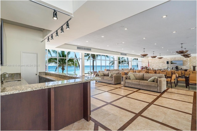 living room featuring recessed lighting, a water view, a healthy amount of sunlight, and visible vents