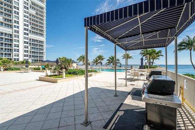 view of patio with a community pool, outdoor dining space, a water view, and a grill