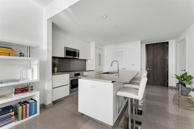 kitchen with stainless steel appliances, modern cabinets, a sink, and white cabinetry