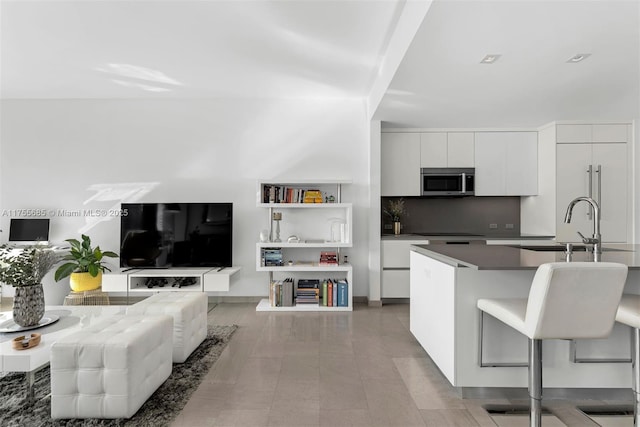 68 SE 6th St Unit 3506, Miami, FL 33131 - kitchen with dark countertops, stainless steel microwave, decorative backsplash, white cabinetry, and modern cabinets