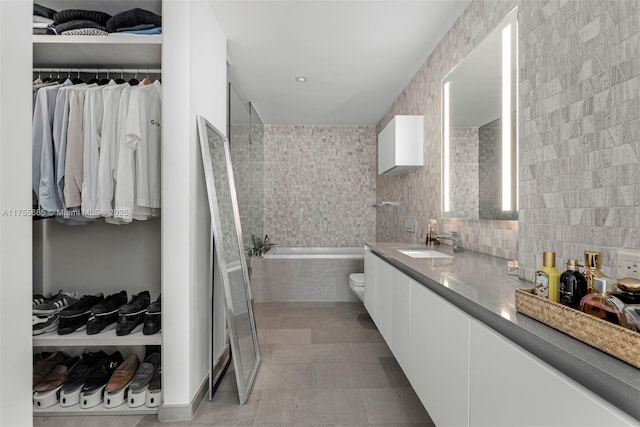 68 SE 6th St Unit 3506, Miami, FL 33131 - full bathroom with tiled bath, tile patterned flooring, a spacious closet, vanity, and tile walls