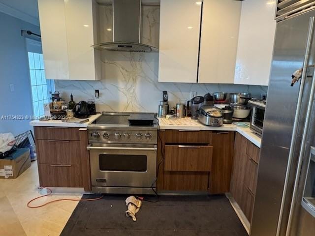 kitchen featuring light countertops, wall chimney range hood, premium appliances, and modern cabinets