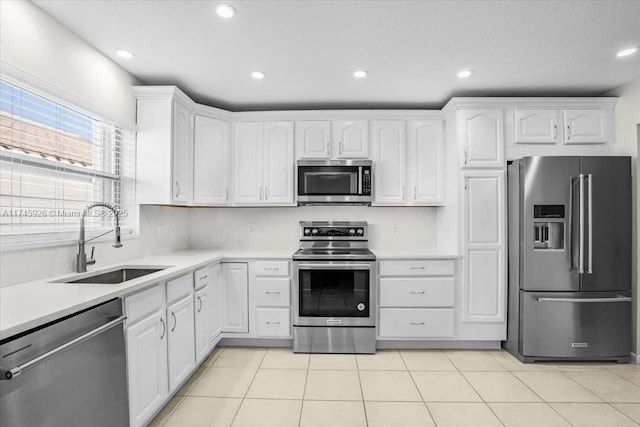 kitchen featuring light tile patterned floors, white cabinetry, stainless steel appliances, and a sink