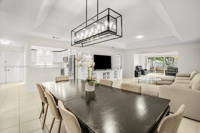 dining room with a tray ceiling, visible vents, baseboards, and light tile patterned floors